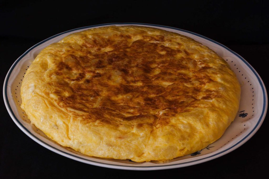 Tortilla de patatas, hiszpański omlet ziemniaczany na dużym białym talerzu