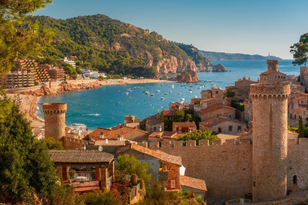 Średniowieczne mury Vila Vella w Tossa de Mar wznoszą się tuż nad piaszczystą plażą.